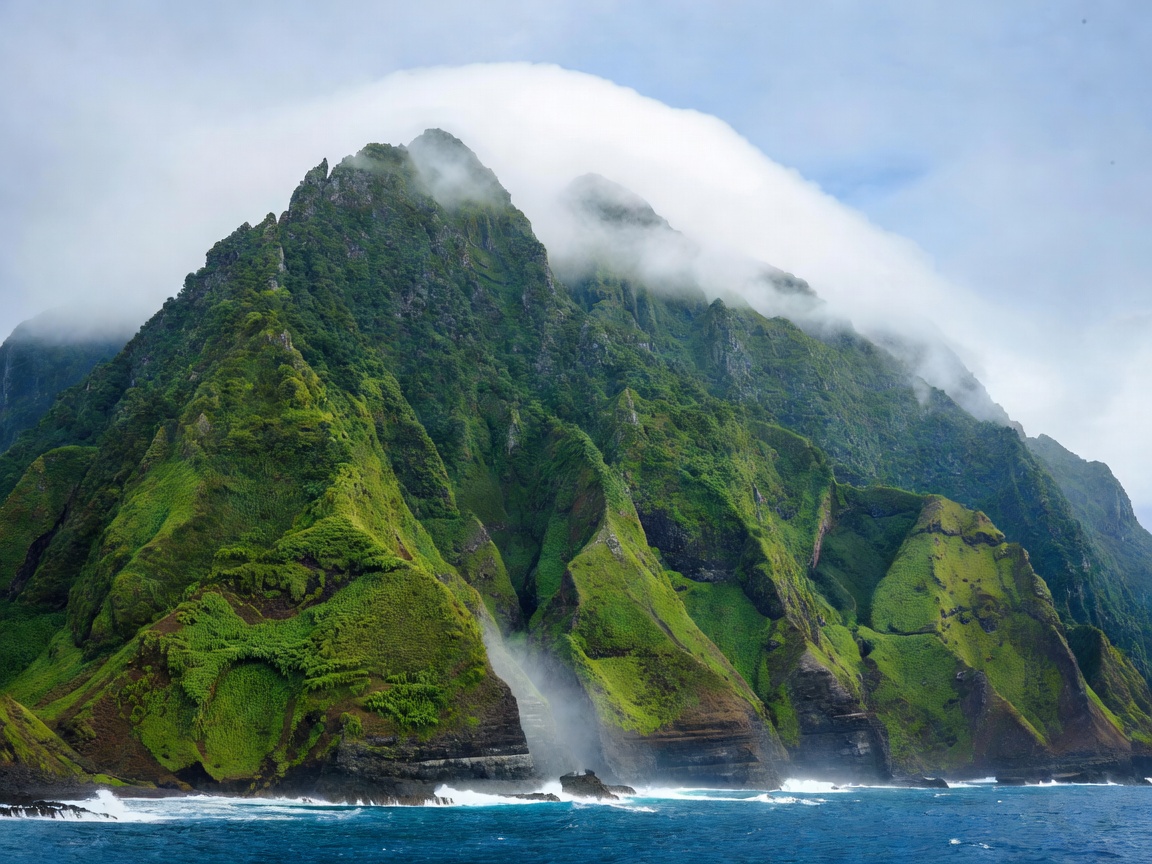 Steep green ridge dropping to the ocean with cloud sitting along the summit line in Madeira
